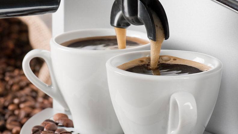 2 coffees being poured with beans surrounding them